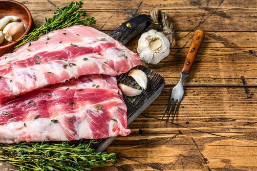 Fresh raw pork rack spareribs with thyme and garlic on cutting board. wooden background. Top view. Copy space.