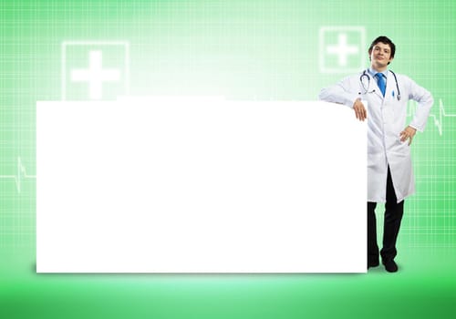 Young handsome doctor with white blank banner. Place your text