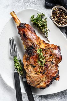 Baked goat leg with herbs. Farm meat. Gray background. Top view.