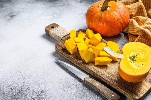 Sliced raw orange pumpkin on a chopping Board. White background. Top view. Copy space