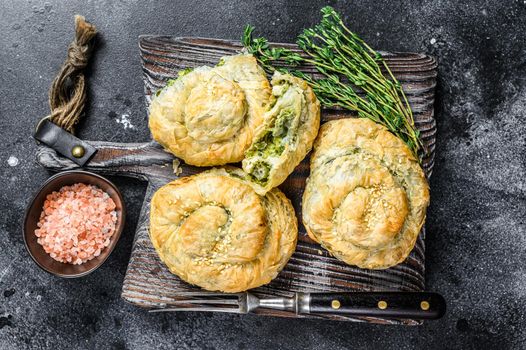 Baked Spanakopita spiral filo pastry puff pie with feta cheese and spinach. Black background. Top view.