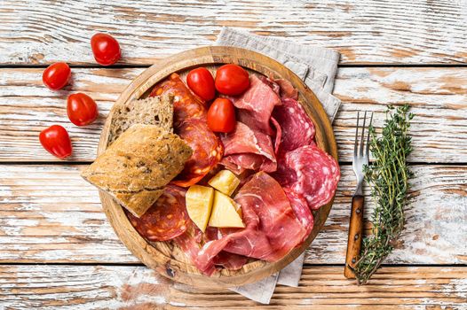 Cold meat plate, charcuterie traditional Spanish tapas on a wooden board. White wooden background. Top view.