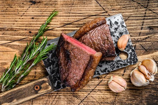 Grilled top sirloin cap beef meat steak on a cleaver. wooden background. Top view.