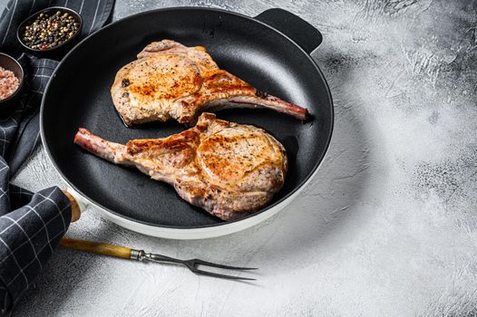 Fried tomahawk pork chop meat steak in a pan. White background. Top view. Copy space.