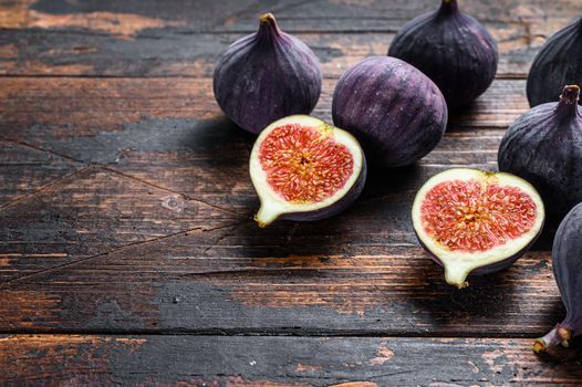 Purple figs on a wooden table. Dark wooden background. Top view. Copy space.