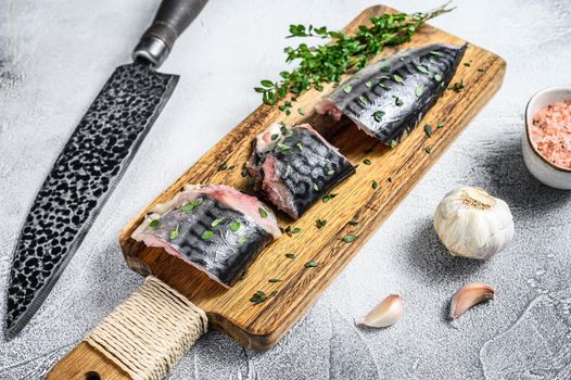 Sliced salted mackerel fish on a wooden cutting board. White background. Top view.