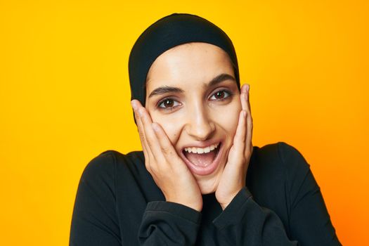Muslim in black hijab posing fashion hand gesture yellow background. High quality photo