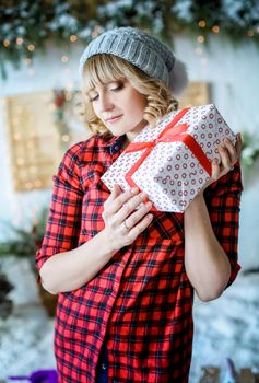 Girl smiles and holds white box with red ribbon in the hands of.