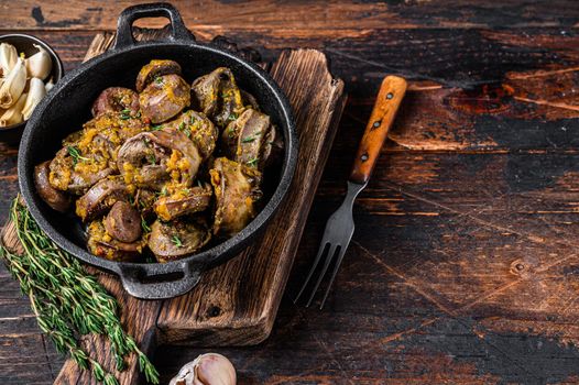 Cooked turkey hearts offals with herbs. Dark wooden background. Top view. Copy space.