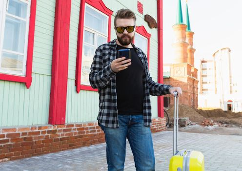 Full body side portrait of happy travel man with suitcase walking along the building in city