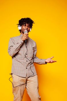 young handsome african american guy student posing cheerful and gesturing on yellow background, lifestyle people concept close up