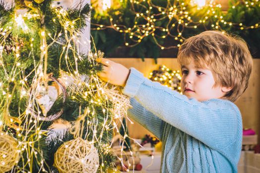 Kid decorating Christmas tree with bauble. Portrait of Santa kid boy with bauble. Happy kids new year