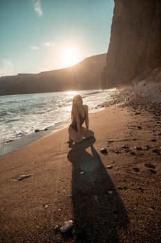 Selective focus. Happy carefree sensual woman with long hair in black swimwear posing at sunset beach. Silhouette of young beautiful playful positive woman outdoor. Summer vacation and trip concept.