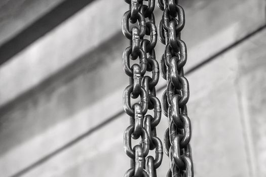 Plant equipment chain with iron links of the lifting mechanism of an overhead crane against the background of an industrial workshop or factory.
