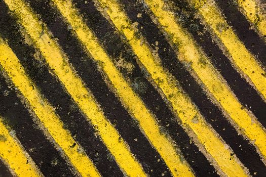Hazardous restricted area designation, black and yellow diagonal lines on concrete texture background.