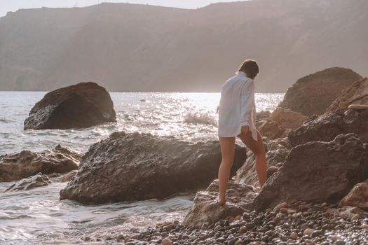 Selective focus. Happy carefree sensual woman with long hair in black swimwear posing at sunset beach. Silhouette of young beautiful playful positive woman outdoor. Summer vacation and trip concept.