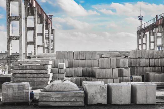 Storage outdoor concrete blocks at a construction site. Concrete and cement building structures in an industrial area against a cloudy sky.
