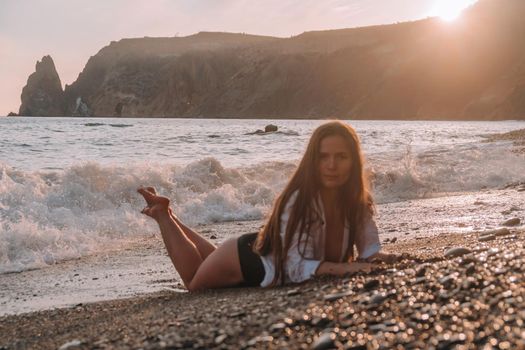 Selective focus. Happy carefree sensual woman with long hair in black swimwear posing at sunset beach. Silhouette of young beautiful playful positive woman outdoor. Summer vacation and trip concept.