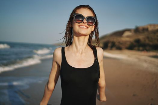 cheerful woman in a black swimsuit walking along the beach tropics summer. High quality photo