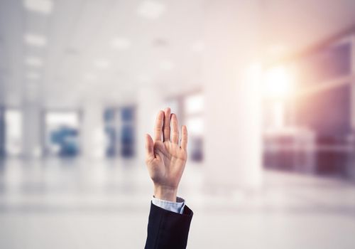 Close of businesswoman hand touching screen with palm and office at background