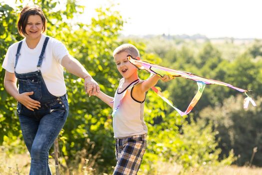 pregnant woman with her son playing a kite