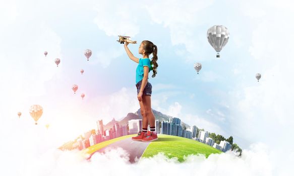 Cute kid girl on city floating island playing with retro plane model