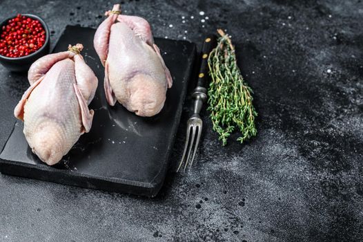 Farm eco friendly raw quails ready for cooking. Black background. Top view. Copy space.