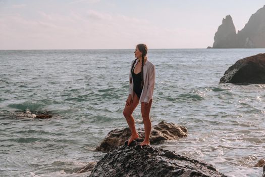 Selective focus. Happy carefree sensual woman with long hair in black swimwear posing at sunset beach. Silhouette of young beautiful playful positive woman outdoor. Summer vacation and trip concept.