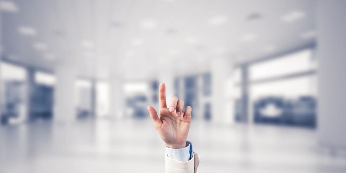 Close of businesswoman hand touching screen with finger and office at background