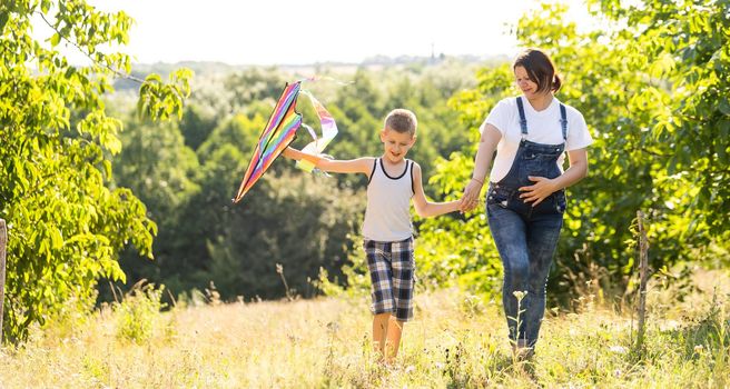 pregnant woman with her son playing a kite