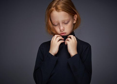 red-haired girl with freckles on her face in a black sweater posing. High quality photo