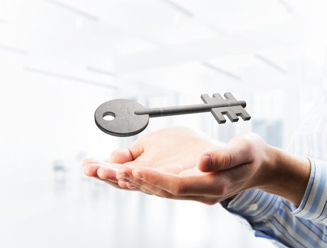 Cropped image of businessman in suit keeping stone key symbol in hands. Mixed media