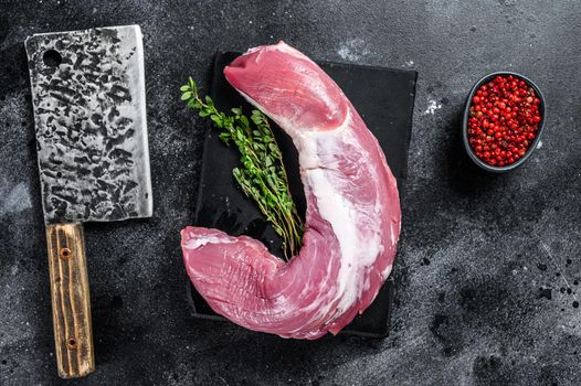 Raw pork tenderloin meat on a marble board. Black background. Top view.