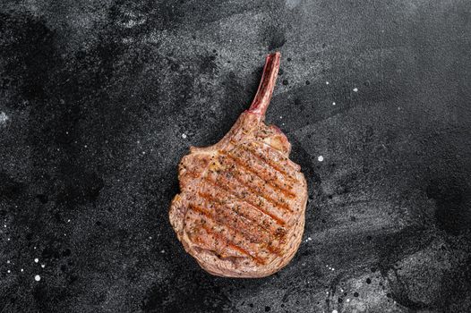 BBQ Grilled Tomahawk beef veal steak on butcher table. Black background. Top view.