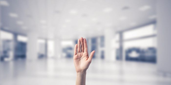 Close of woman hand touching screen with palm and office at background