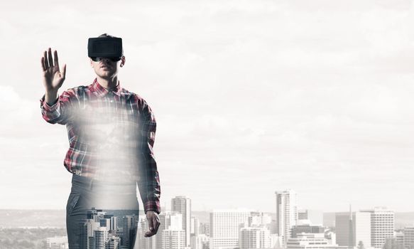 Young man with virtual reality headset or 3d glasses over cityscape background
