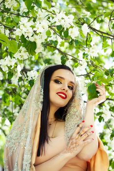 young pretty indian girl in jewelry and veil posing cheerful happy smiling in green park, lifestyle people concept close up