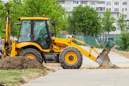 Bulldozer or excavator industrial machine removes sand on the background of buildings at a construction site.