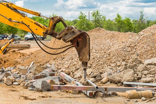 Mechanical equipment industrial vibratory hammer for drilling stones and concrete structures in the background of a construction site.