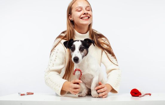 pretty young blond girl with her little cute dog wearing Santas red hat at Christmas holiday isolated on white background, lifestyle people concept close up