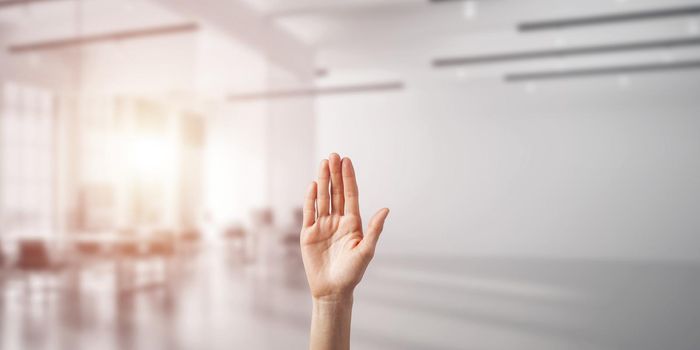 Close of woman hand touching screen with palm and office at background