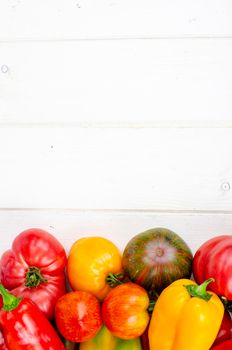 Multicolored sweet peppers and tomatoes on wooden table. Studio Photo
