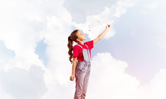 Cute kid girl in overalss with paper plane in hand