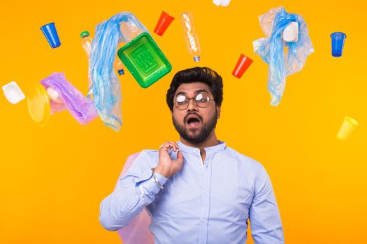 Problem of trash, plastic recycling, pollution and environmental concept - man carrying garbage bag on yellow background.