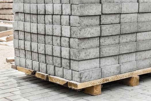 A pile of packed paving stone slabs industrial tile sidewalk materials on wooden pallet at a construction site.