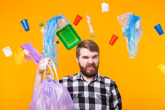 Environmental pollution, plastic recycling problem and ecology problem concept - displeased man holding garbage bag on yellow background