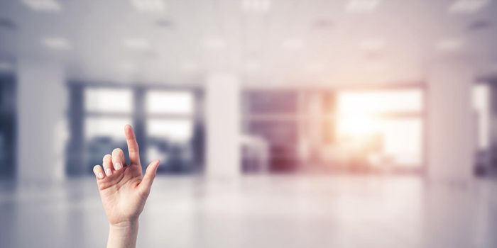 Close of woman hand touching screen with finger and office at background