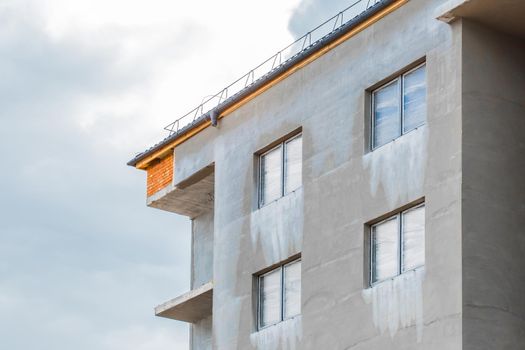 Concrete cement facade with a windows of a new under construction modern city house on a construction site.