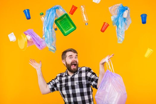 Problem of trash, plastic recycling, pollution and environmental concept - funny man carrying garbage for recycling on yellow background.