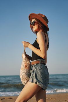 cheerful woman in a hat with sunglasses walking with a bag. High quality photo